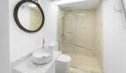 Moderno baño con ducha de mármol, lavamanos tipo recipiente y espejo vintage redondo en la casa de ciudad Felanitx
