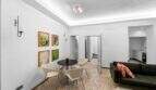 Luminosa sala de estar con mesa de comedor redonda, imágenes de arte pop en la pared y sofá moderno en la casa de ciudad Felanitx