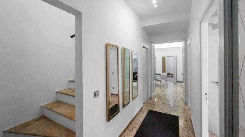 Luminoso pasillo de entrada con suelo de terrazo, espejos de pared, escalera y vista a través de la casa de ciudad Felanitx