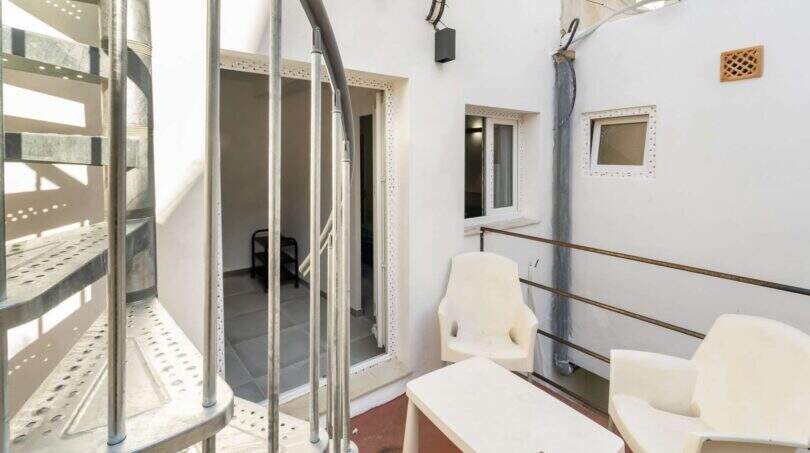 Terraza con sillas de plástico blanco, escaleras metálicas y acceso a la casa de ciudad en Felanitx