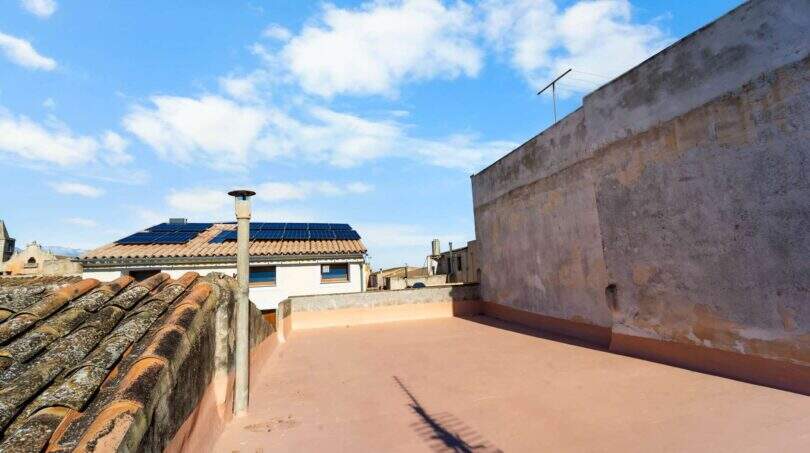 Espaciosa terraza en la azotea con vista a edificios vecinos y paneles solares, casa de ciudad mediterránea en Felanitx