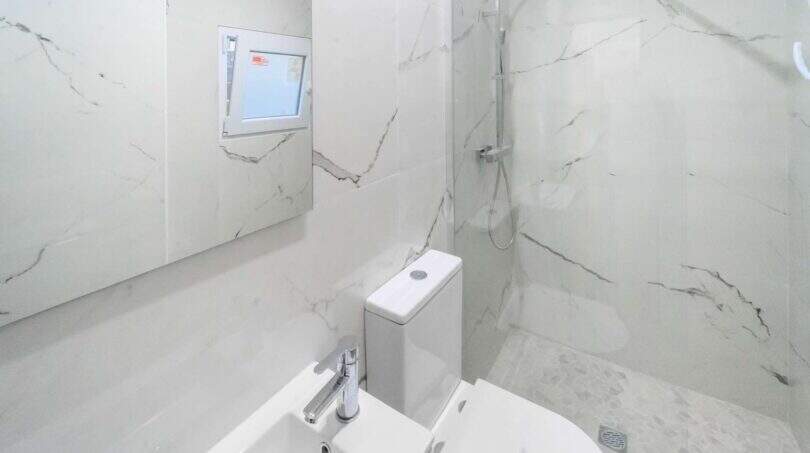 Moderno baño con azulejos de mármol, ducha, inodoro y lavamanos en la casa de ciudad Felanitx