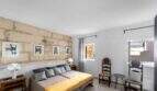Dormitorio con pared de piedra natural, cama doble con colcha amarilla y sillas de madera antiguas en la casa urbana Felanitx