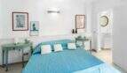 Luminoso dormitorio con cama doble en color turquesa, mesillas de noche verde menta y baño en suite en la casa de ciudad Felanitx
