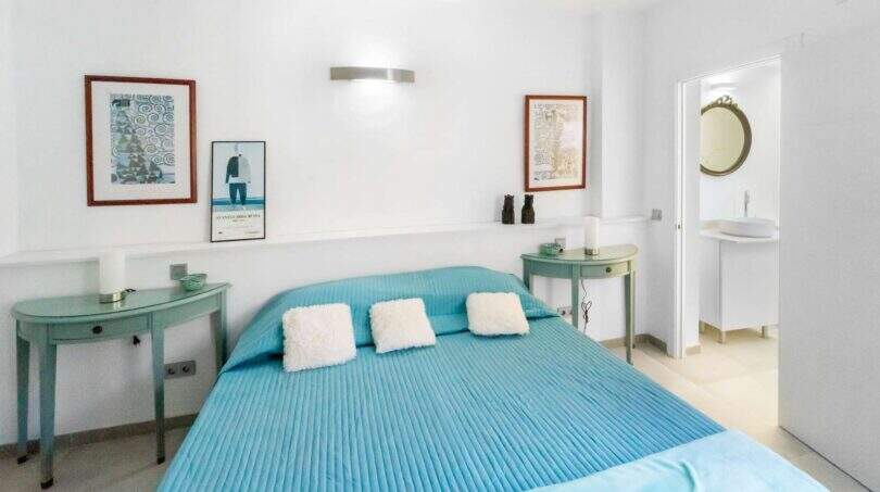 Luminoso dormitorio con cama doble en color turquesa, mesillas de noche verde menta y baño en suite en la casa de ciudad Felanitx