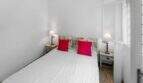 Luminoso dormitorio con cama doble, cojines rojos y mesillas de noche rústicas en la casa de ciudad Felanitx