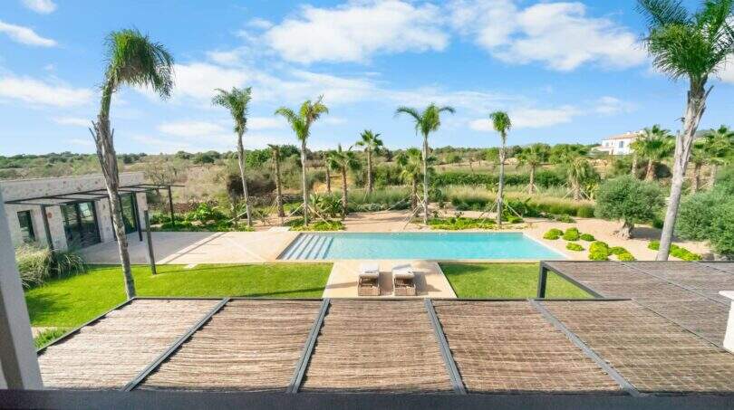 Poolbereich der Finca bei Portocolom mit Palmen, Liegestühlen und Blick auf mediterrane Landschaft