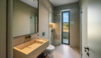 Modernes Badezimmer der Finca Portocolom mit Naturstein-Waschtisch, Dusche und Fensterblick ins Grüne