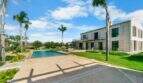 Finca Portocolom: Außenansicht mit Swimmingpool, Palmen, weitläufiger Terrasse und mediterranem Herrenhaus unter blauem Himmel.