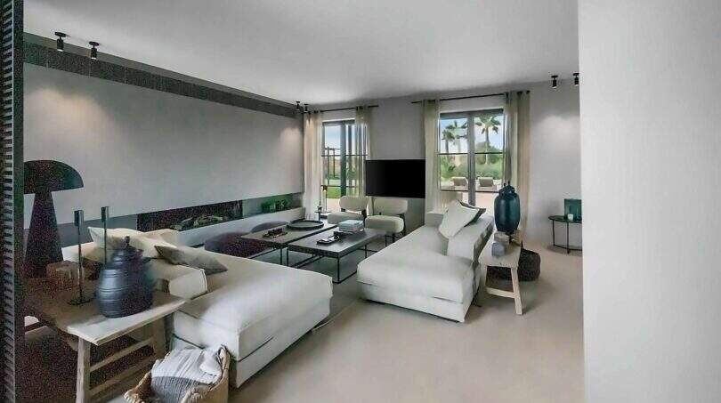 Helles Wohnzimmer der Finca bei Portocolom mit weißen Sofas, Flachbild-TV und Blick auf Palmen