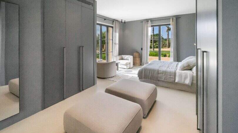 Elegantes Schlafzimmer der Finca Portocolom mit Einbauschränken, Doppelbett und Gartenblick durch französische Türen