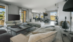 Lichtdurchflutetes Wohnzimmer der Finca Portocolom mit modernen Sofas, offenem Essbereich und Blick ins Grüne