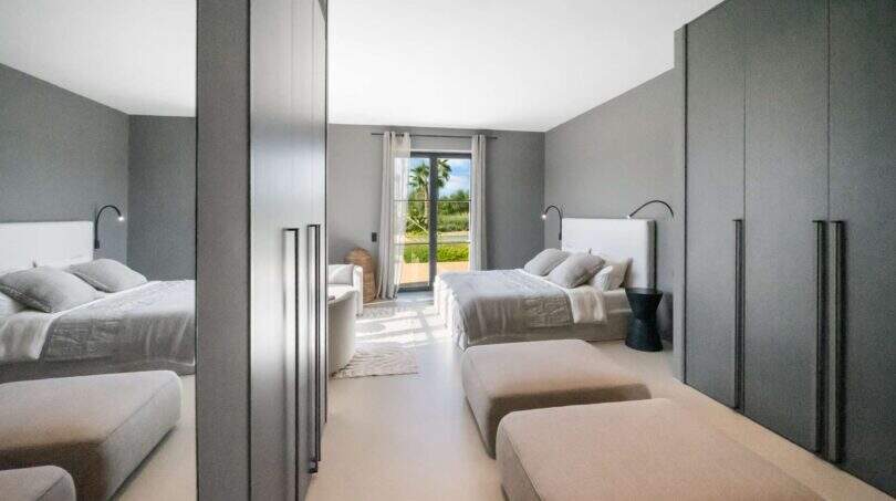 Modernes Schlafzimmer der Finca Portocolom mit Doppelbett, Spiegelschrank und Terrasse mit Palmenblick