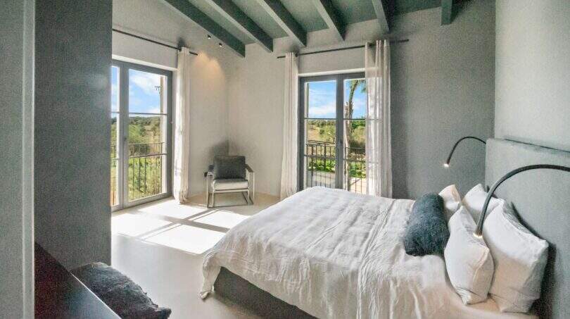Helles Schlafzimmer der Finca Portocolom mit Doppelbett, Holzbalkendecke und Balkon mit Landschaftsblick