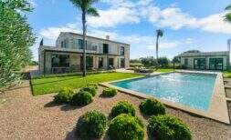 Finca Portocolom: piscina de estilo mediterráneo con zona ajardinada, palmeras y una villa de piedra natural en una ubicación de ensueño