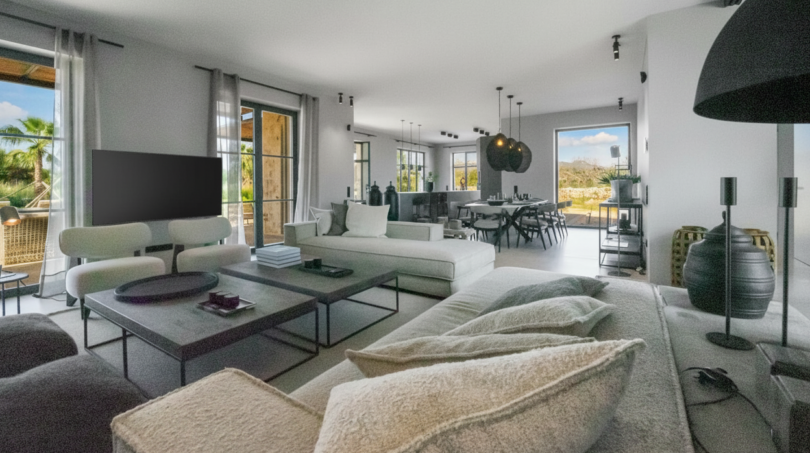 Helles Wohnzimmer der Finca bei Portocolom mit modernen Sofas, Esstisch und Panoramablick auf die Landschaft.