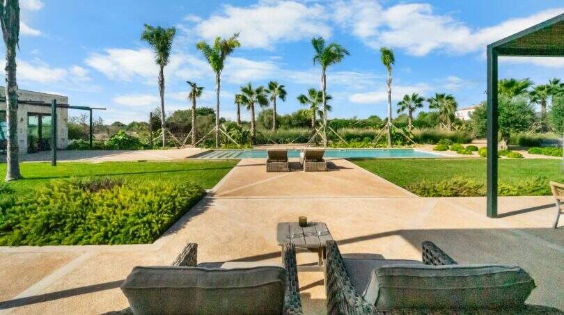 Weitläufiger Pool mit Liegestühlen, Palmen und gepflegtem Garten der Finca nahe Cala Sa Nau in Portocolom