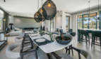 Elegantes Esszimmer der Finca Portocolom mit langen Marmortisch, Designer-Hängeleuchten und Blick ins Grüne