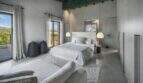 Helles Schlafzimmer der Finca Portocolom mit weißem Doppelbett, Pendelleuchten und Balkon mit Landschaftsblick.