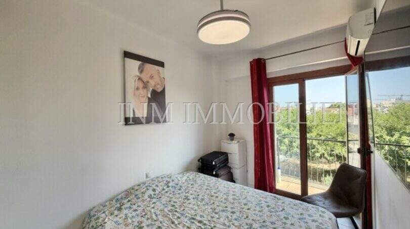 Luminoso dormitorio con cama doble, aire acondicionado y acceso a balcón con vista al verde en Palma