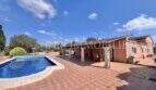 Außenbereich der Finca in Llucmajor mit Pool, Terrasse und überdachtem Sitzbereich an sonnigem Tag.
