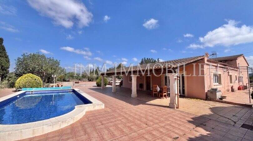 Außenbereich der Finca in Llucmajor mit Pool, Terrasse und überdachtem Sitzbereich an sonnigem Tag.