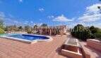 Weitläufige Terrasse mit Pool und Springbrunnen der Finca in Llucmajor unter blauem Himmel