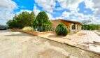 Außenansicht Finca Llucmajor: Bungalow mit überdachter Terrasse, Säulengang, Zypressen und großem Vorplatz.