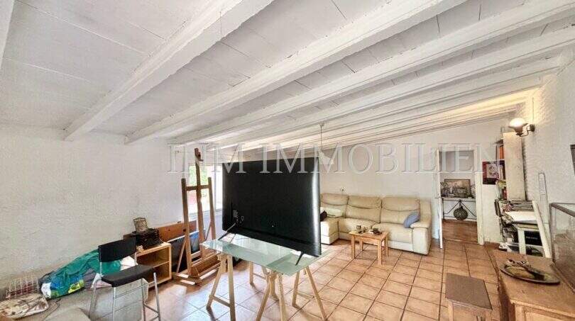 Wohnzimmer der Finca in Llucmajor mit Holzbalkendecke, Terrakottaboden und großem TV