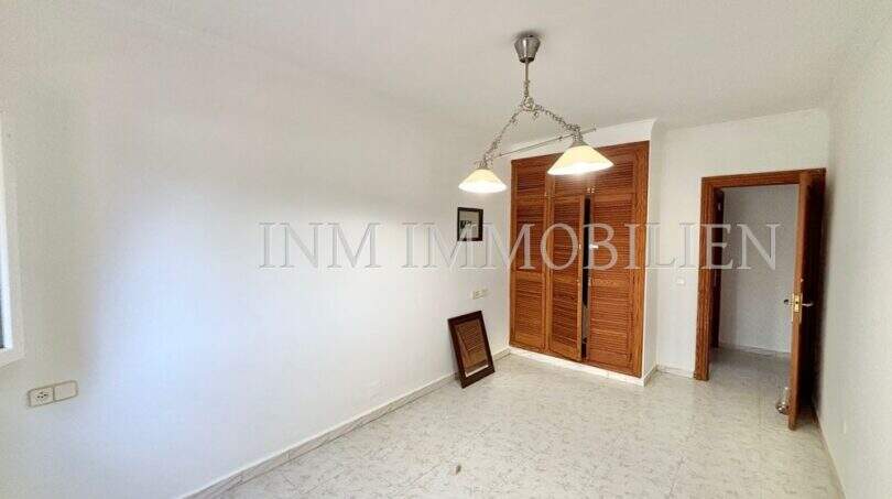 Helles Schlafzimmer mit Einbauschrank aus Holz, Pendelleuchte und hellem Fliesenboden in Finca Llucmajor
