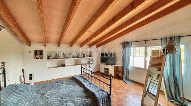 Schlafzimmer mit Holzbalkendecke, Terrakottaboden und Doppelbett in Finca Llucmajor