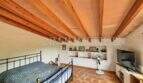 Schlafzimmer mit Holzbalkendecke, Doppelbett, Wandregalen und Terrakottaboden in Finca Llucmajor