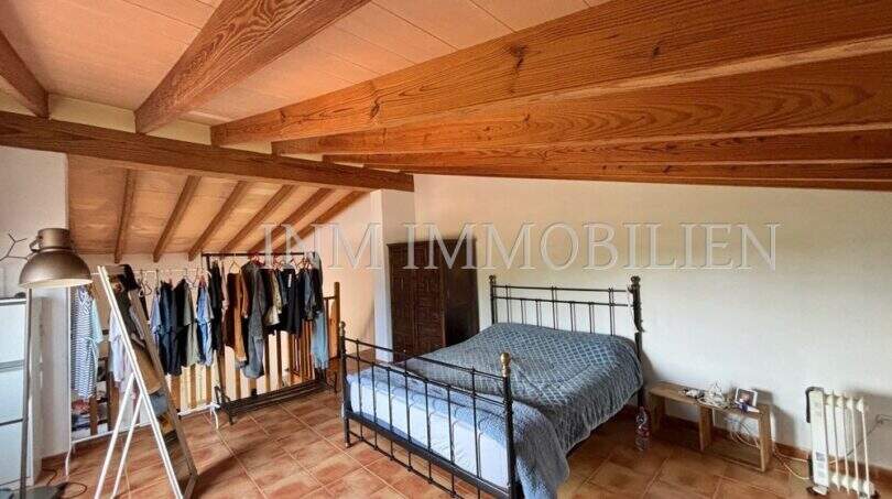 Schlafzimmer mit Doppelbett, Holzbalkendecke und Terrakottaboden in Finca Llucmajor