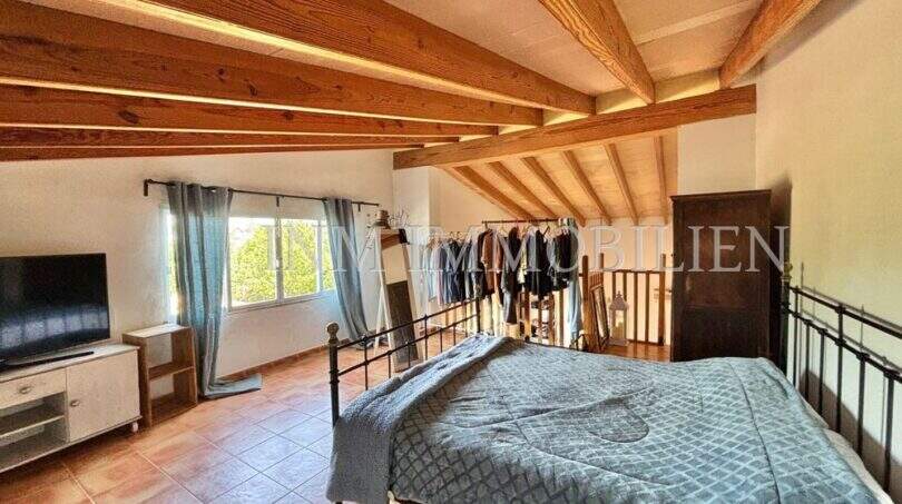 Rustikales Schlafzimmer mit Holzbalkendecke, Terrakottaboden und Eisenbett in Finca Llucmajor