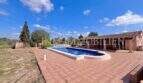 Großer Pool mit Terrasse der Finca in Llucmajor, Wohngebäude mit Überdachung im Hintergrund