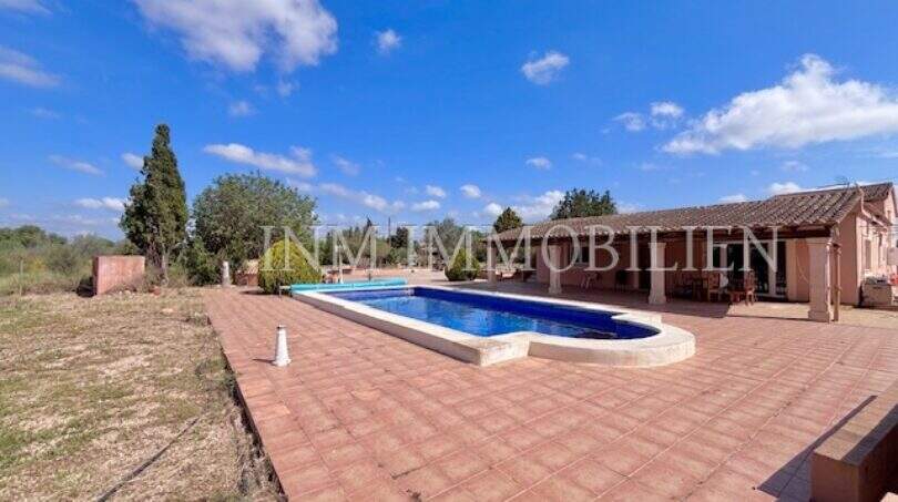 Großer Pool mit Terrasse der Finca in Llucmajor, Wohngebäude mit Überdachung im Hintergrund