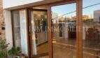 Área de terraza de una villa en Marratxí con elegantes puertas correderas de madera y cristal y vista a la cocina moderna.