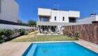 Casa moderna de nueva construcción en Puig de Ros con piscina privada, jardín bien cuidado y terraza bajo cielo azul.