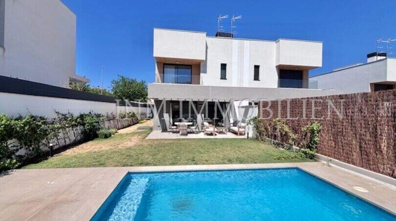 Casa moderna de nueva construcción en Puig de Ros con piscina privada, jardín bien cuidado y terraza bajo cielo azul.