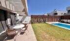 Terraza moderna con mesa de comedor, jardín bien cuidado y piscina privada de una casa de nueva construcción en Puig de Ros