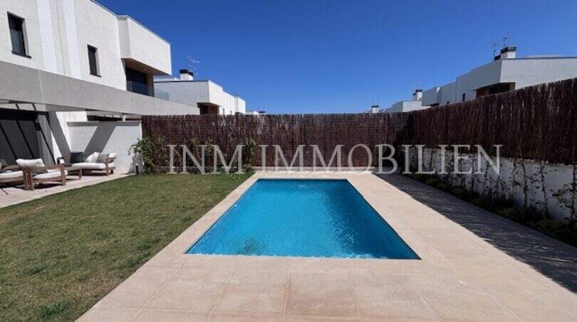 Piscina privada con terraza y zona de césped de una casa moderna de nueva construcción en Puig de Ros, Llucmajor.