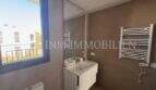 Cuarto de baño moderno con toallero calefactor, lavabo y ventana en la casa de nueva construcción en Puig de Ros