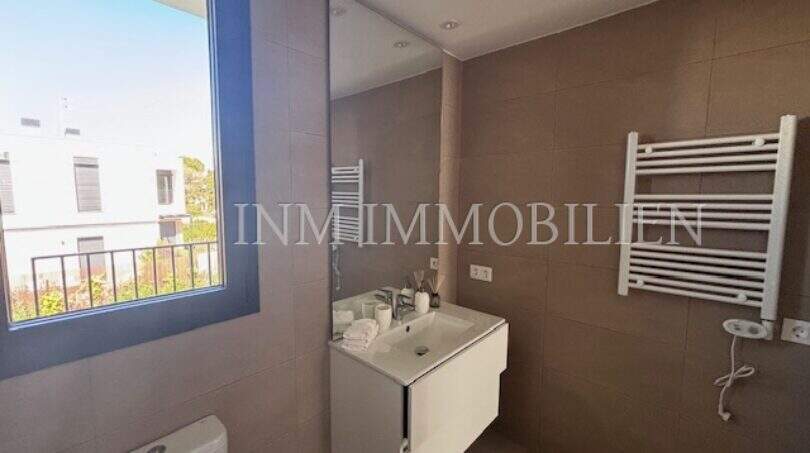Cuarto de baño moderno con toallero calefactor, lavabo y ventana en la casa de nueva construcción en Puig de Ros