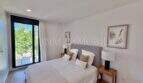 Dormitorio luminoso con cama doble, mesillas de madera y acceso a la terraza en la casa de nueva construcción Puig de Ros