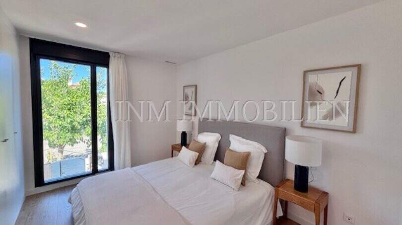 Dormitorio luminoso con cama doble, mesillas de madera y acceso a la terraza en la casa de nueva construcción Puig de Ros