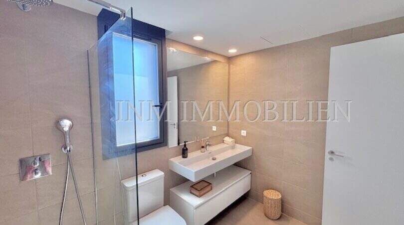Cuarto de baño moderno con ducha de lluvia, lavabo mural e inodoro en casa de nueva construcción Puig de Ros, Llucmajor