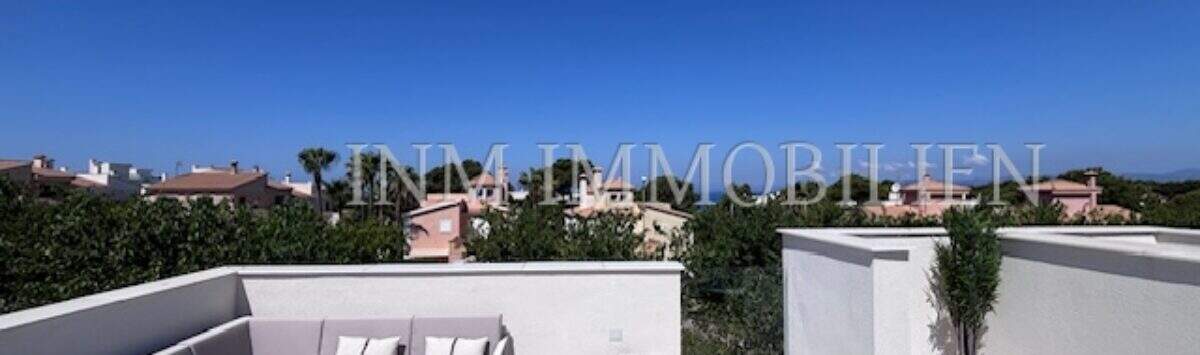 Terraza en la azotea soleada con muebles lounge y vista panorámica sobre Puig de Ros en Llucmajor, Mallorca.