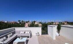 Terraza en la azotea soleada con muebles lounge y vista panorámica sobre Puig de Ros en Llucmajor, Mallorca.