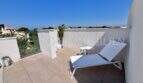 Terraza en la azotea soleada con tumbonas y vistas al mar de una casa de nueva construcción exclusiva en Puig de Ros