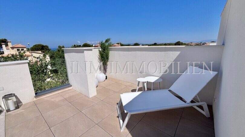 Terraza en la azotea soleada con tumbonas y vistas al mar de una casa de nueva construcción exclusiva en Puig de Ros